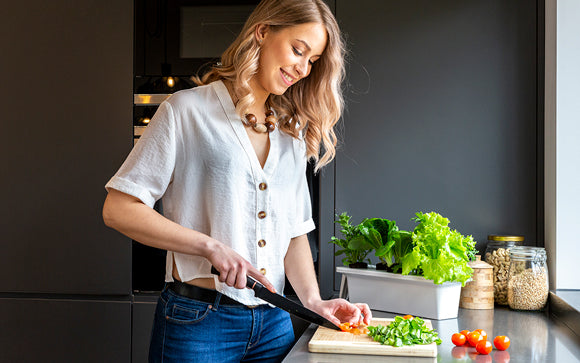 Woman cooking with greens from a tray