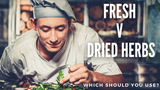 Smiling chef topping a pizza with herbs.