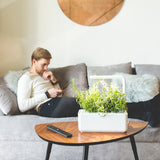 Man sitting on sofa with smart garden on table